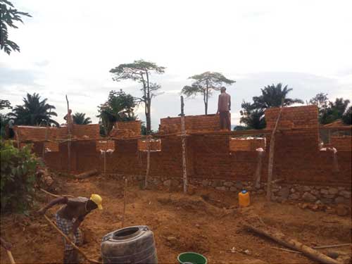 Les maçons montent un échafaudage de fortune pour l'élévation des murs de l'école de Visiki en RDC